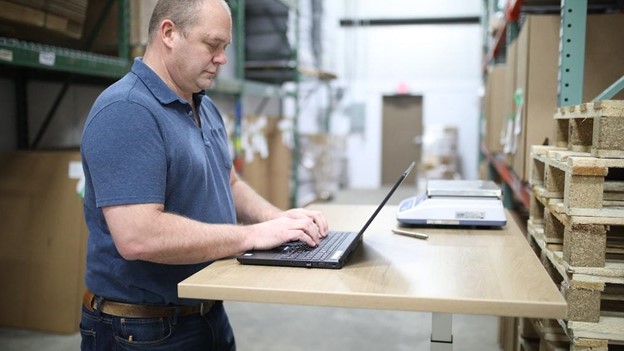 Man stands at a desk on his laptop typing